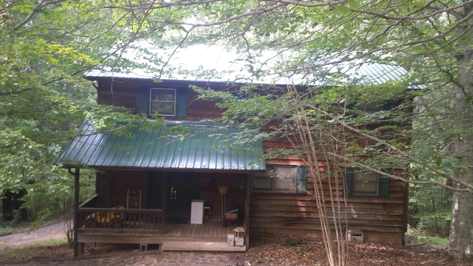Green metal roof and covered porch on a log cabin in Nineveh