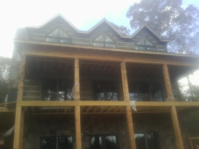 Dormers and porch framing on a large log home under construction — Roof Coating work by our crew in Nineveh