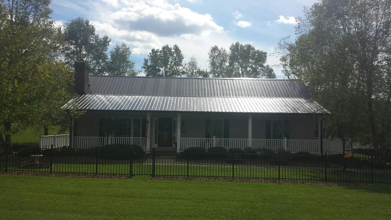 Gray metal roof on a brick ranch with a full width front porch — Gutter Guard Installation work by our crew in Nineveh