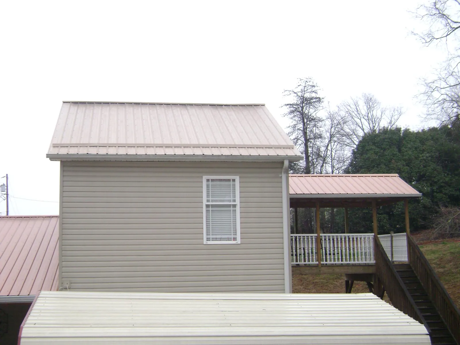 Tan metal roofs on a two story addition and attached porch, from a Roof Replacement job in Nineveh