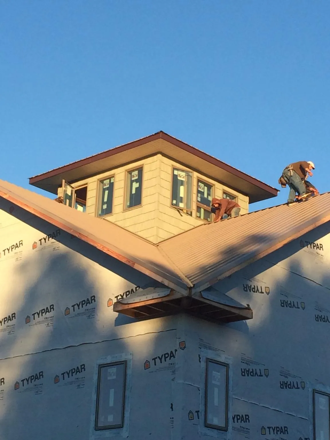 Roofers working around a rooftop cupola on a new metal roof at sunset — Roof Waterproofing in Nineveh by Roofing Brothers